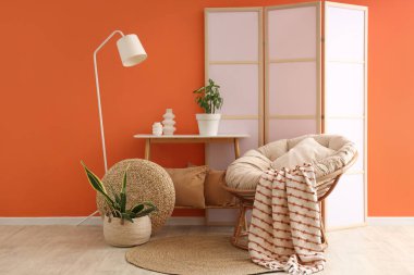 Beyaz lamba, koza sandalye ve katlanır ekranlı şık bir oturma odası.