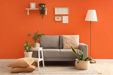 İçinde lamba, gri kanepe ve bitkiler olan şık bir oturma odası.