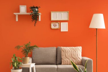 İçinde lamba, gri kanepe ve bitkiler olan şık bir oturma odası.