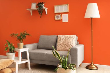 İçinde lamba, gri kanepe ve bitkiler olan şık bir oturma odası.