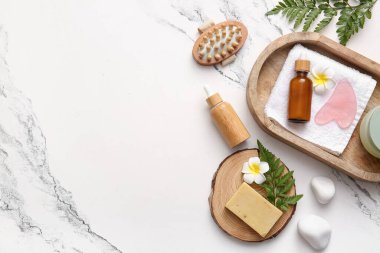 Tepsi, masaj vücut fırçası ve mermer zemin üzerinde kozmetik ürünler içeren spa kompozisyonu