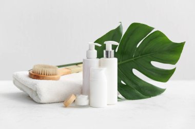 Beyaz arka planda tropikal yaprak, şişe ve kozmetik ürünler içeren spa kompozisyonu, yakın plan