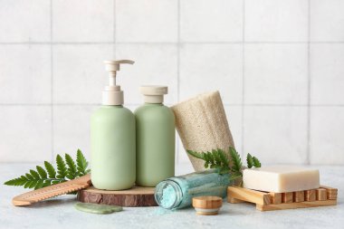 Tepsi, sabun ve kozmetik ürünleri içeren spa kompozisyonu gri grunge masasında, fayans duvarının yanında, yakın plan.