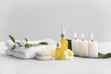 Beyaz arka planda havlu, taş ve şişe kozmetik ürünleri içeren spa kompozisyonu, yakın plan