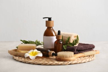 Hasır hasırlı spa kompozisyonu, masaj vücut fırçası ve bej grunge arka planda kozmetik ürünleri şişeleri, yakın plan