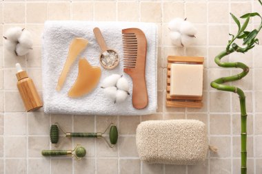 Yüz masajı aletleri, havlu, pamuk çiçekleri ve bej kaplamalı bir şişe kozmetik ürünü içeren spa kompozisyonu