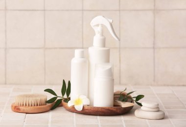 Bej karo arka planda taşlar, tepsi ve şişe kozmetik ürünleri içeren spa kompozisyonu, yakın plan