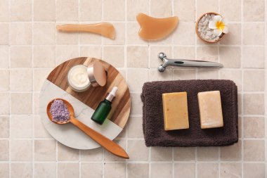 Tepsi, yüz masajı aletleri, havlu, kavanoz ve bej kaplamalı kozmetik ürünleri içeren spa kompozisyonu