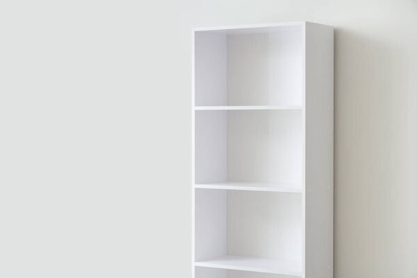 Empty bookshelf near light wall