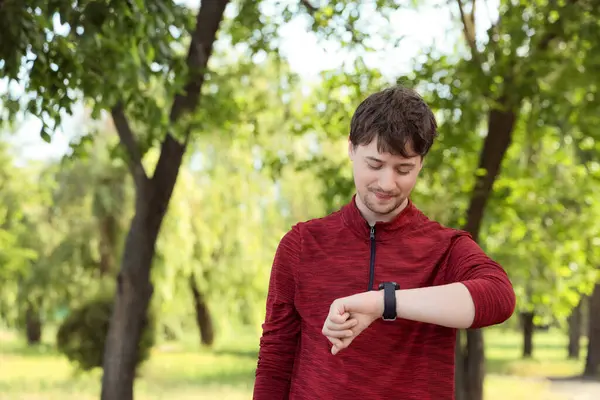 Erkek koşucu parkta akıllı saati kontrol ediyor