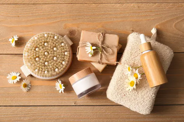 Ahşap zemin üzerinde papatya çiçekleri, kavanoz ve bir şişe kozmetik ürünleri olan kompozisyon, yakın plan