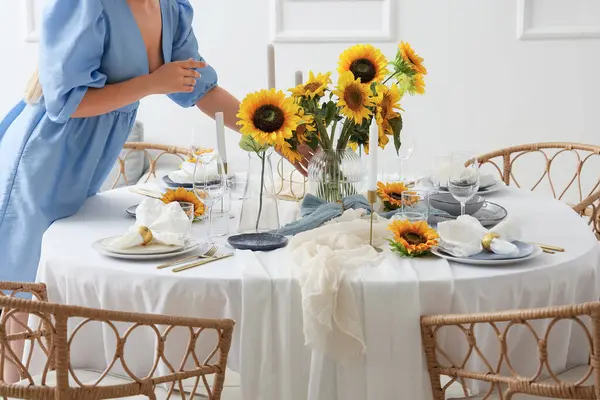 Yemek masasını güzel ayçiçekleriyle süsleyen genç bir kadın.