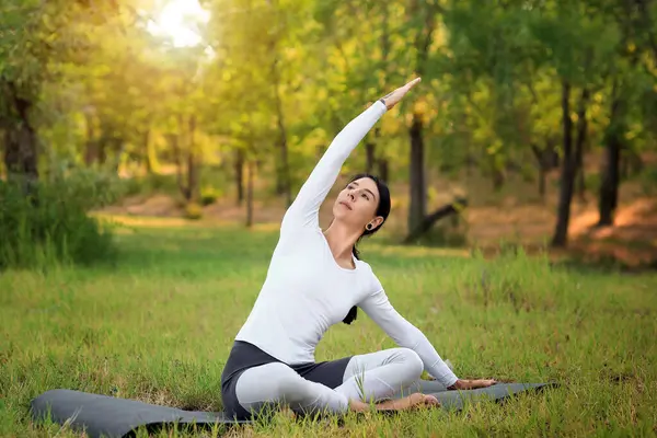 Parkta yoga yapan genç bir kadın.