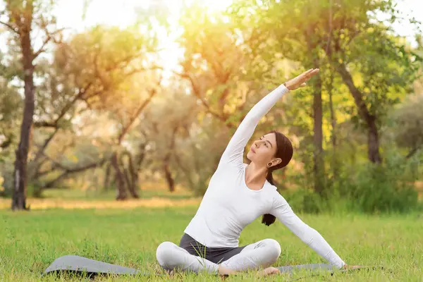 Parkta yoga yapan genç bir kadın.