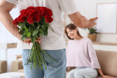 Evdeki sevgilisi için kırmızı gülleri olan genç bir adam.