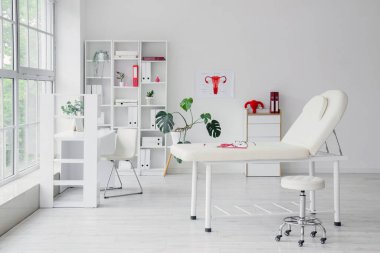 İş yeri, raf ünitesi ve kanepesi olan jinekoloğun bürosu.