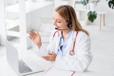 Olgun kadın doktor klinikte online danışmanlık yapıyor.