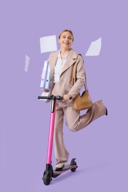 Dosyaları ve düşen kağıtları olan olgun bir iş kadını. Leylak arka planda elektrikli scooter kullanıyor.