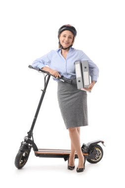 Kasklı, klasörlü ve beyaz arka planda elektrikli scooter kullanan olgun bir iş kadını.