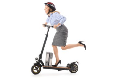 Beyaz arka planda elektrikli scooter kullanan, kasklı, olgun bir iş kadını.