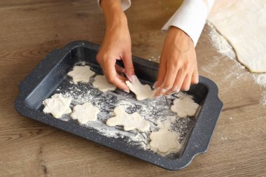 Kadın elleri yemek tepsisine çiğ kurabiye koyar, yakın plan.