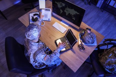 Askeri bilgisayarı olan bir asker gece masa başında telefon alıyor.