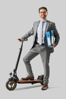 Dosyalar ve arka planda elektrikli scooterı olan yakışıklı bir iş adamı.