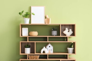 Boş çerçeveli raflar, bitkiler ve yeşil duvarın yanındaki dekorlar.