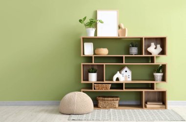 Boş çerçeveli kitaplık, bitkiler ve yeşil duvarın yanındaki dekorlar.