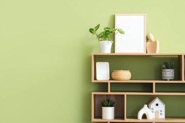 Boş çerçeveli raflar, bitkiler ve yeşil duvarın yanındaki dekorlar.