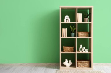 Hasır sepetli kitaplık ve yeşil duvarın yanında bitkiler.