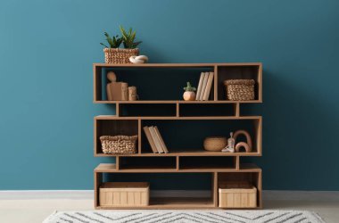 Odada mavi duvarın yanında sepetler olan bir kitaplık.