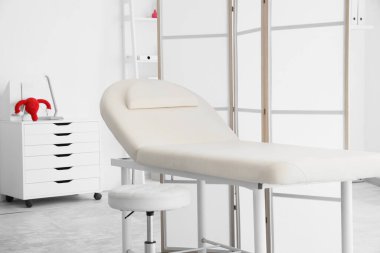 Kanepesi ve katlanır perdesi olan jinekoloğun ofisi.