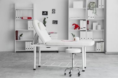 Kanepesi, raf ünitesi ve bitkileri olan jinekoloğun ofisi.