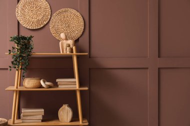 Kahverengi duvarın yanında bitki ve dekorla ahşap kitaplık.