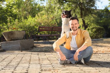 Parkta oturan şirin Border Collie köpekli genç adam.