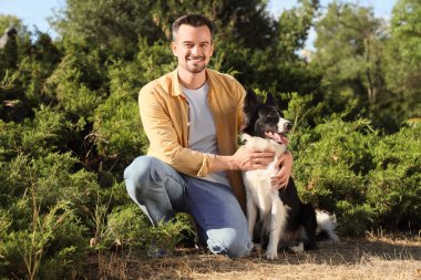 Parkta oturan şirin Border Collie köpekli genç adam.