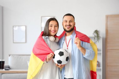 İspanya bayrağı taşıyan genç çift evde futbol seyrediyor.