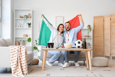 Meksika bayrağıyla evde futbol izleyen genç bir çift.