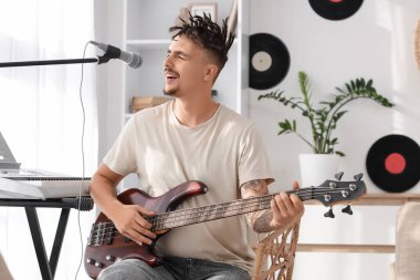 Rastalı genç adam evde elektro gitar çalıyor.