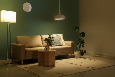 Geceleri karanlık oturma odasının içinde kanepe, sepet ve parlayan lambalar.