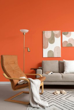 Gri koltuğu, koltuğu ve lambası olan şık bir oturma odası.