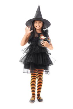 Cadılar Bayramı için cadı gibi giyinmiş tatlı Asyalı kız ve beyaz arka planda şekerler.