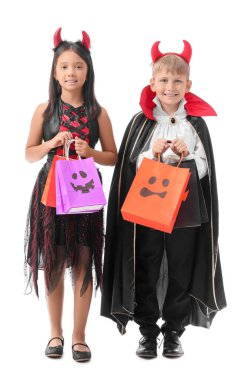Cadılar Bayramı için giyinmiş küçük çocuklar ve beyaz arka planda hediye çantaları.