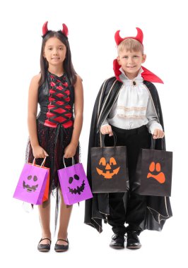 Cadılar Bayramı için giyinmiş küçük çocuklar ve beyaz arka planda hediye çantaları.