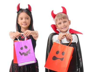 Cadılar Bayramı için giyinmiş küçük çocuklar ve beyaz arka planda hediye çantaları.