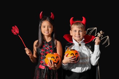 Cadılar Bayramı için giyinmiş küçük çocuklar ve siyah arka planda şekerler.