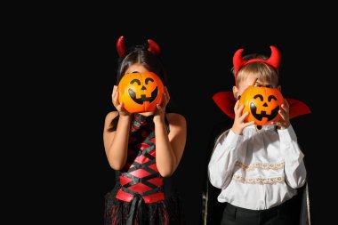 Cadılar Bayramı için giyinmiş küçük çocuklar ve siyah arka planda şekerler.
