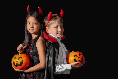 Cadılar Bayramı için giyinmiş küçük çocuklar ve siyah arka planda şekerler.