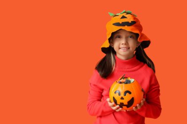 Cadılar Bayramı için giyinmiş, turuncu arka planda şekerlemeleri olan tatlı Asyalı kız.